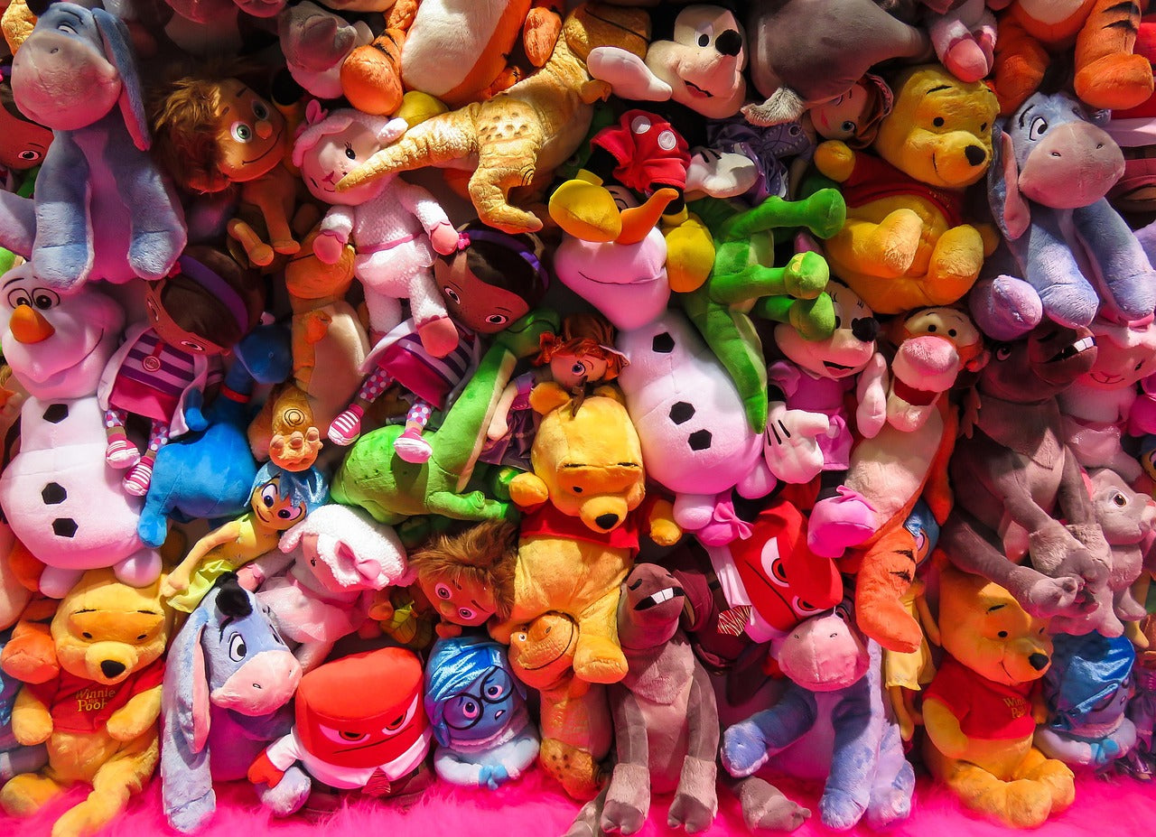 Colorful pile of plush toys including popular characters like Winnie the Pooh, Olaf, and Mickey Mouse for kids' gifts and playtime.